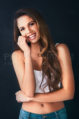 Buy stock photo Studio portrait of an attractive young woman posing against a dark background