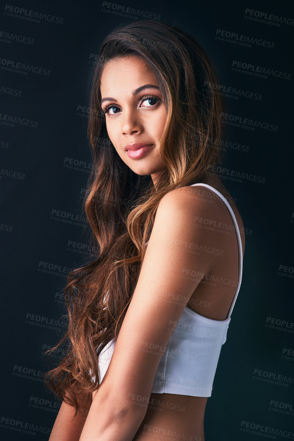 Buy stock photo Studio portrait of an attractive young woman posing against a dark background