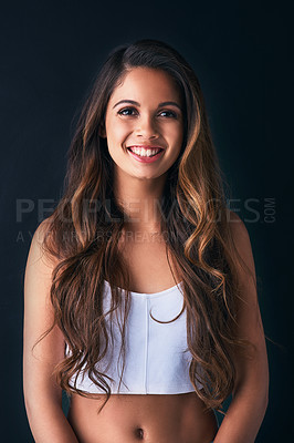 Buy stock photo Studio portrait of an attractive young woman posing against a dark background