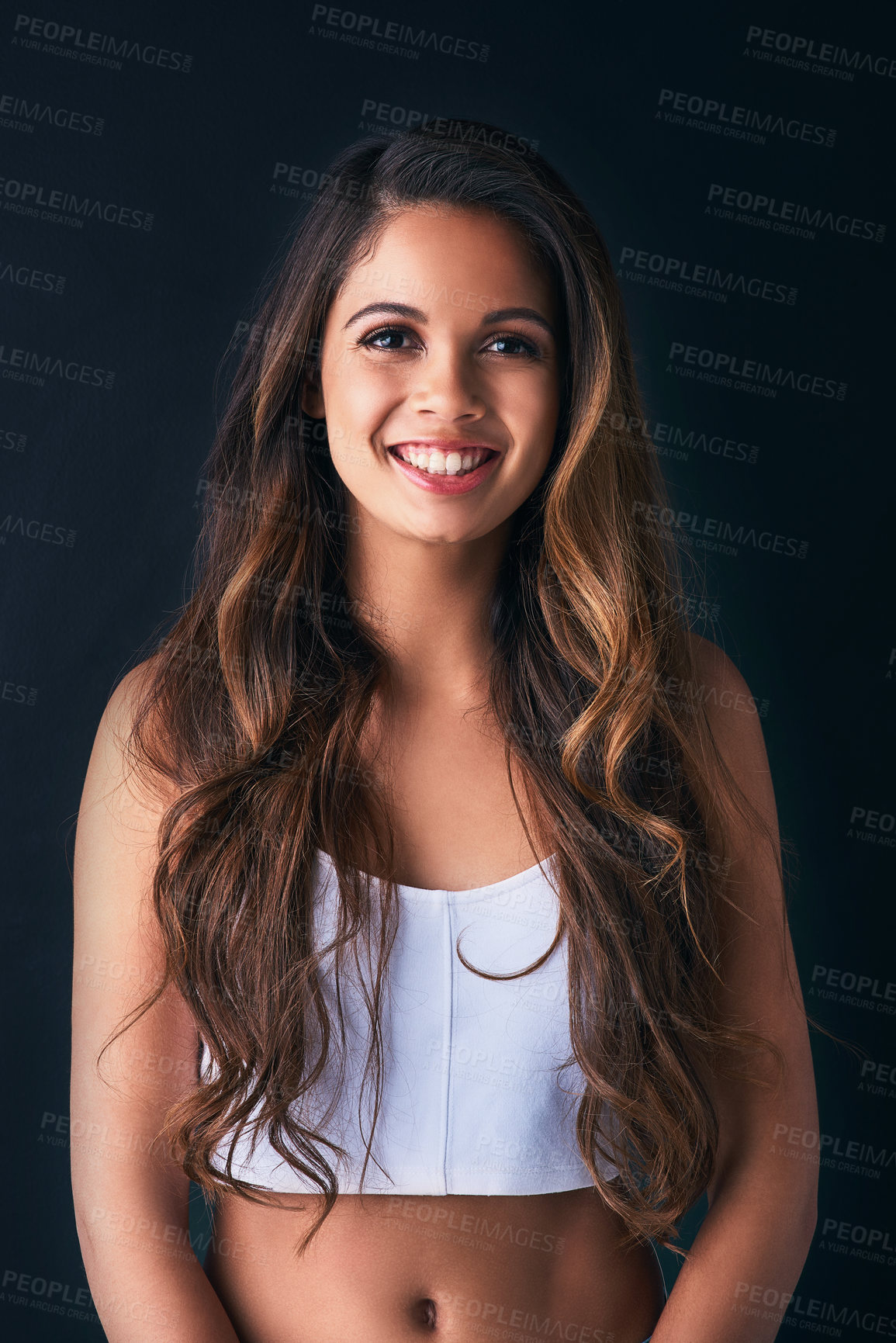 Buy stock photo Studio portrait of an attractive young woman posing against a dark background