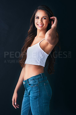 Buy stock photo Studio portrait of an attractive young woman posing against a dark background