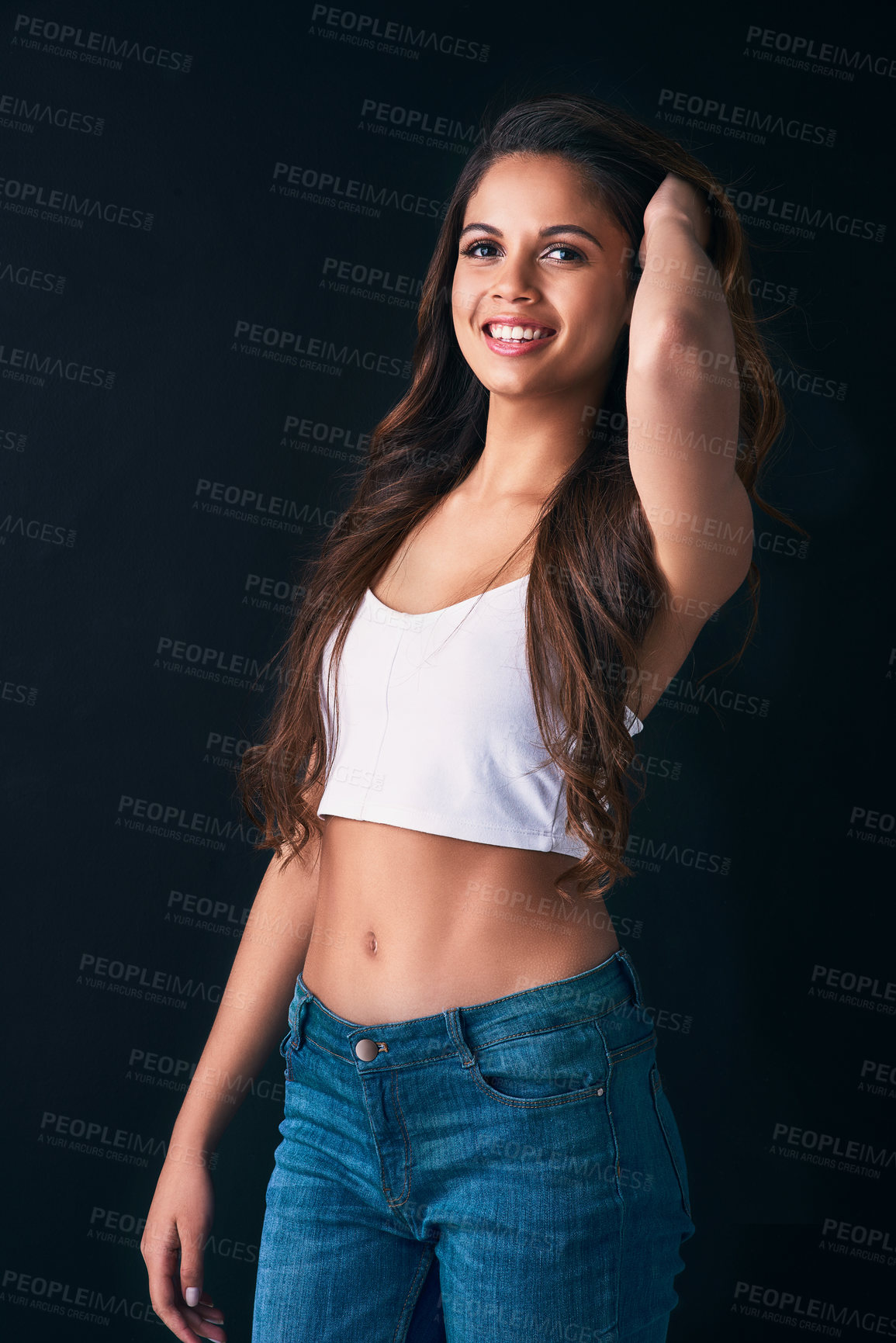 Buy stock photo Studio portrait of an attractive young woman posing against a dark background