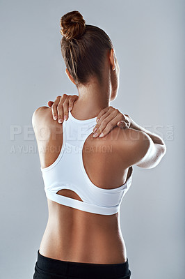 Buy stock photo Studio shot of an athletic young woman holding her neck in pain against a grey background