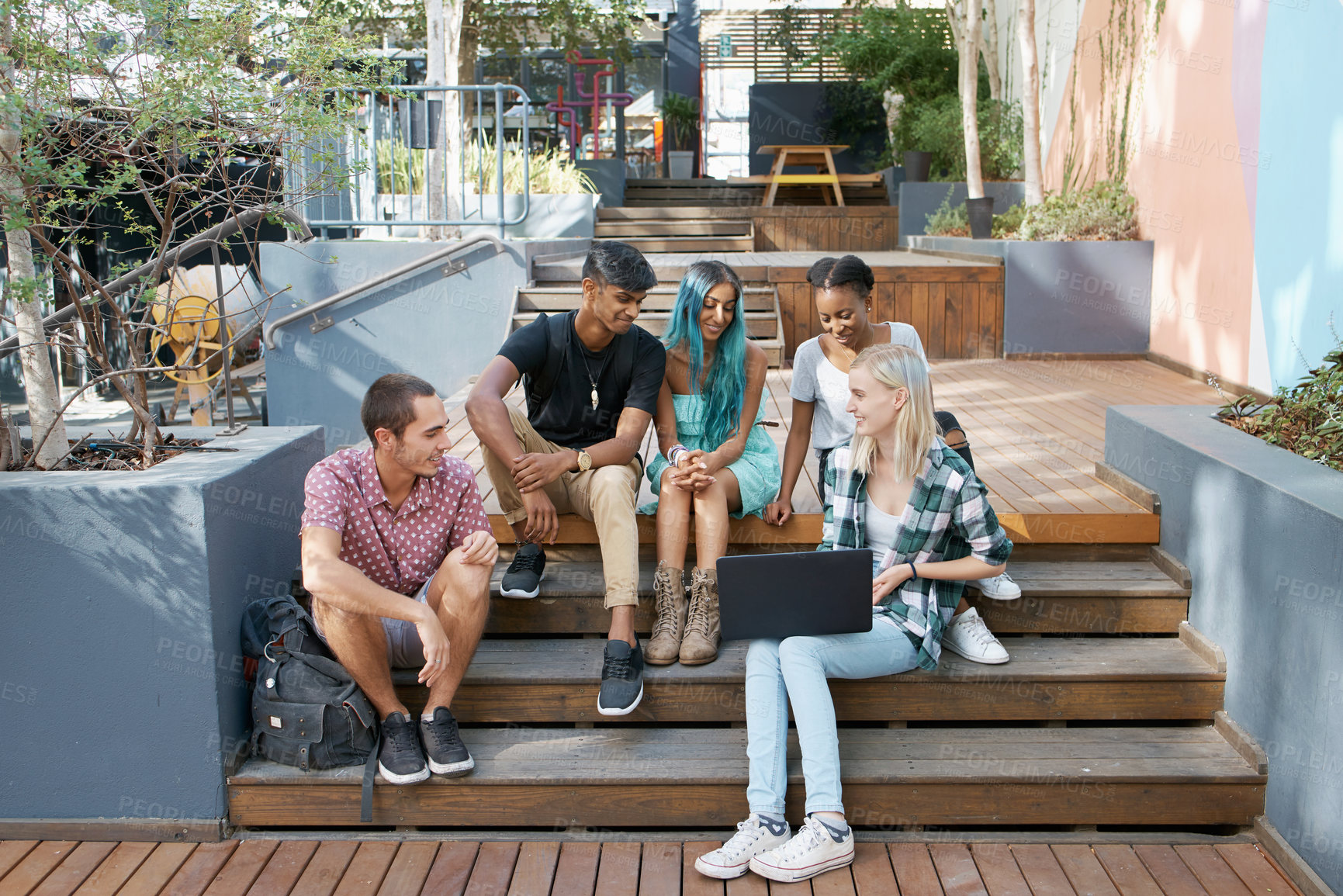 Buy stock photo Shot of a group of young students enjoying a break outdoors on campus