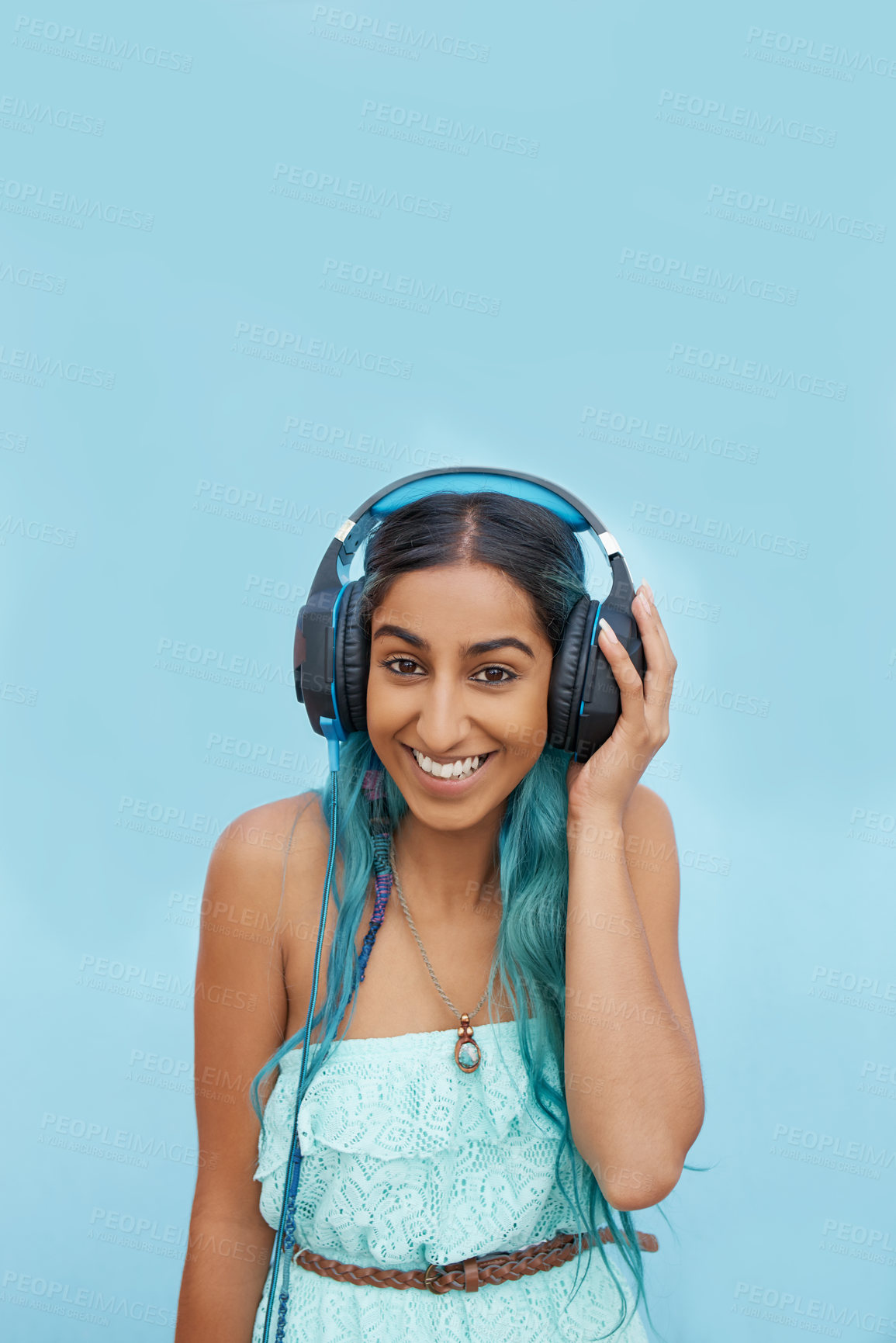 Buy stock photo Headphones, smile and portrait of girl in studio with audio for music streaming, online radio or podcast. Indian student, happy and person with tech for media, sound and connection on blue background