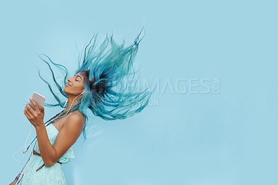 Buy stock photo Girl, earphones and hair on air in studio, phone and online for streaming playlist on blue background. Female person, mockup space and dancing with energy, kpop and app for song and music for fun