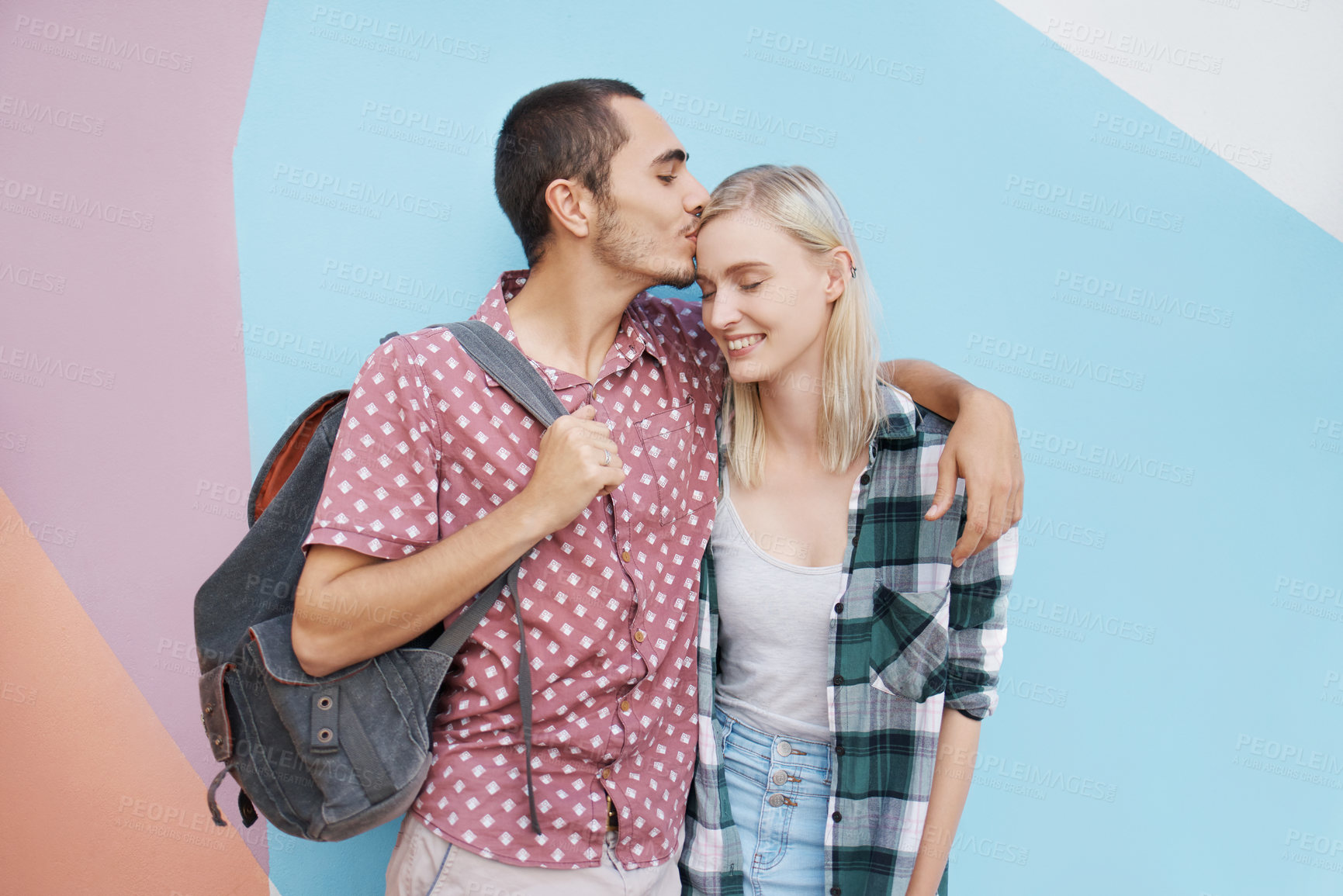 Buy stock photo Couple, students and kiss forehead in studio for care with education or knowledge, hug and bonding for love. Man, girl and together, color block and scholarship for university, college and mockup.