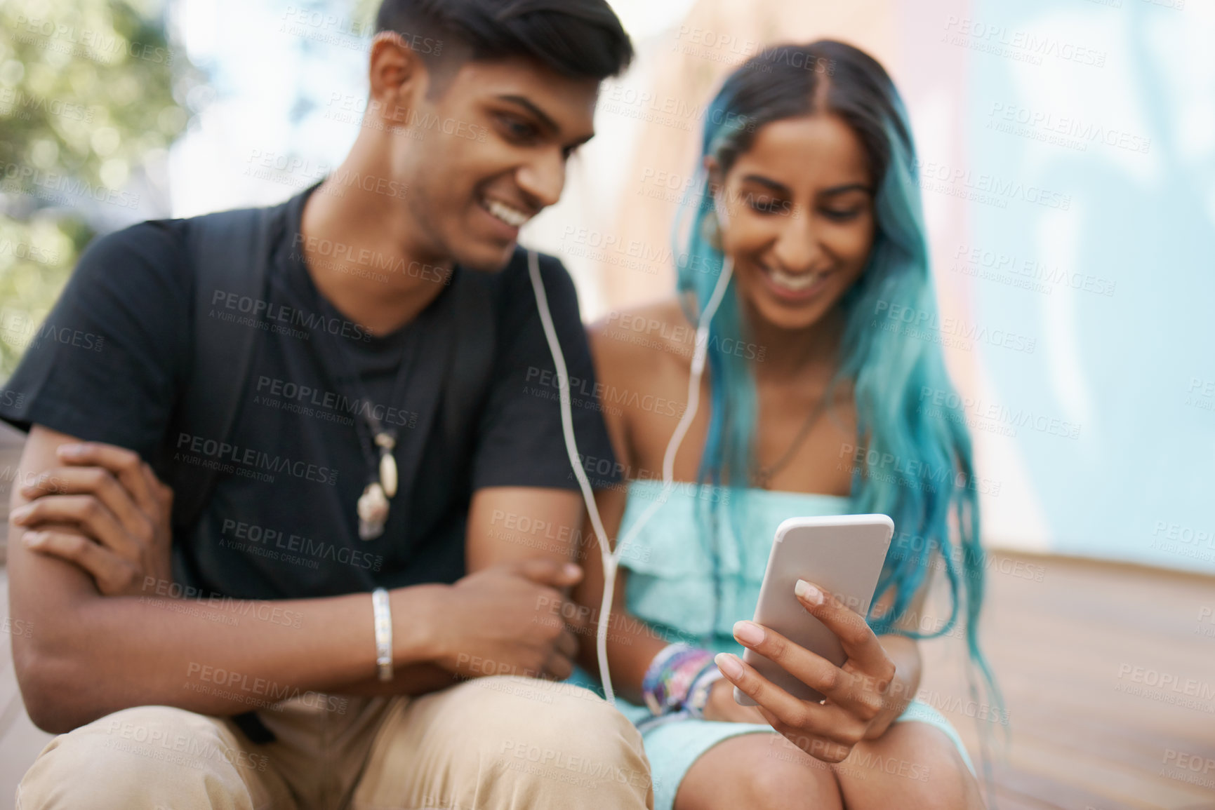 Buy stock photo Couple, earphones and student with mobile phone for funny meme, podcast or watch video on campus. Headphones, Indian man and woman with smartphone for social media, online app or web browsing