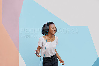 Buy stock photo Shot of a cheerful young woman dancing outside and listening to music on her phone with her eyes closed