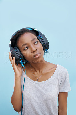 Buy stock photo Thinking, music and black woman with headphones in city for sound, track or listening to podcast on blue background. Streaming, earphones or gen z student outdoor with radio, playlist or audio ebook