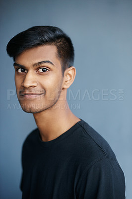 Buy stock photo Young, Indian and man in portrait with smile, confident and proud with student isolated on blue background. Casual, tshirt and positive with gen z for college, cool and calm with model in studio
