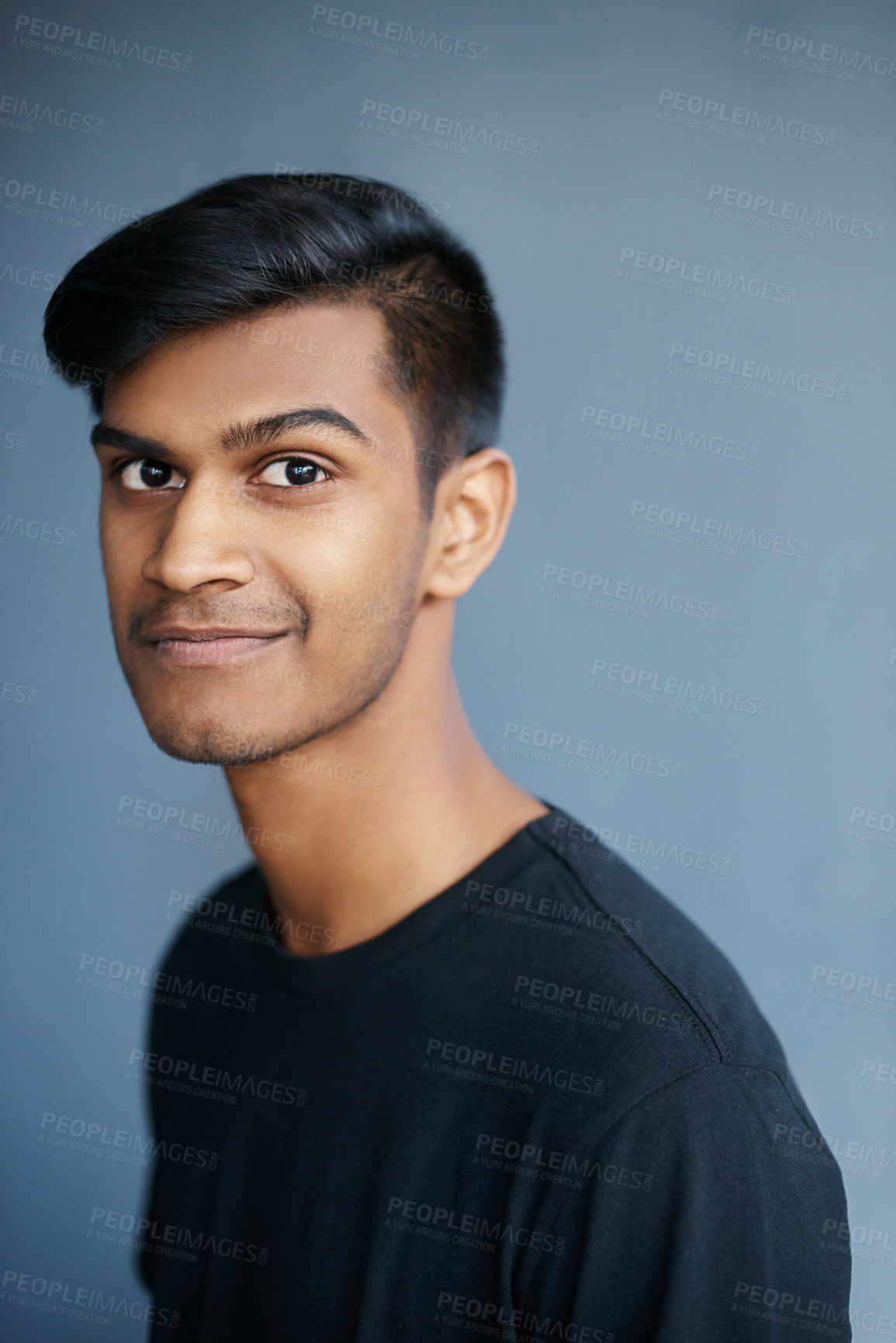 Buy stock photo Young, Indian and man in portrait with smile, confident and proud with student isolated on blue background. Casual, tshirt and positive with gen z for college, cool and calm with model in studio