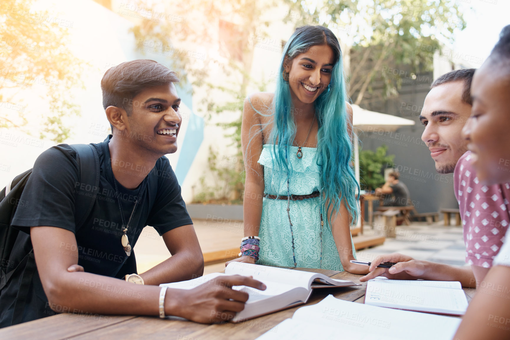 Buy stock photo Students, friends and learning outdoor at university with books, listening and teamwork for education on campus. People, gen z group study and research with smile, diversity or college break by table