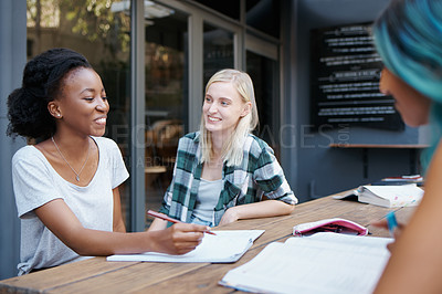 Buy stock photo Students, group and talking outdoor at university with books, writing or learning for education on campus. Friends, gen z people and funny conversation with smile, diversity or college break by table