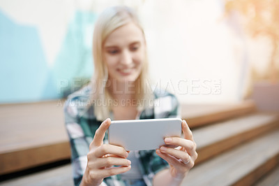 Buy stock photo Shot of a young woman sitting on the steps outside and using a mobile phone