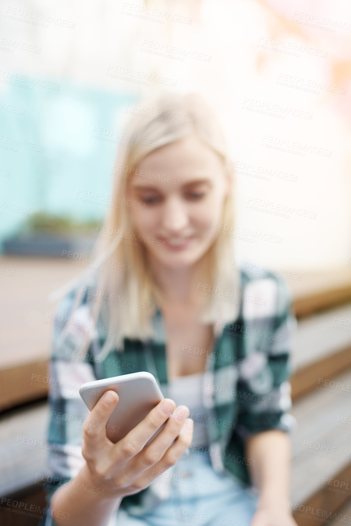 Buy stock photo Shot of a young woman sitting on the steps outside and using a mobile phone