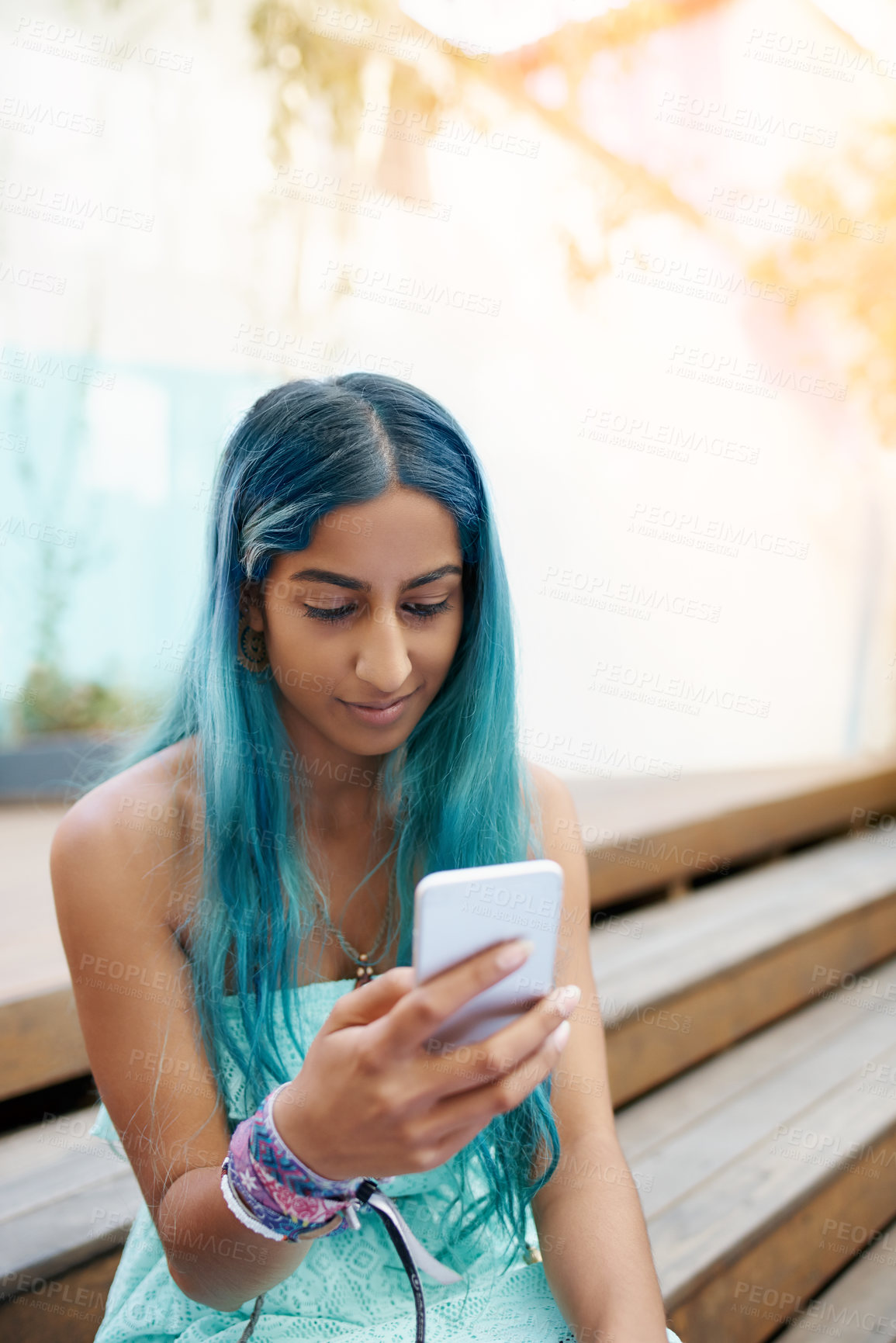 Buy stock photo Shot of a young woman sitting on the steps outside and using a mobile phone