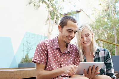 Buy stock photo Shot of a young couple using a digital tablet together outside
