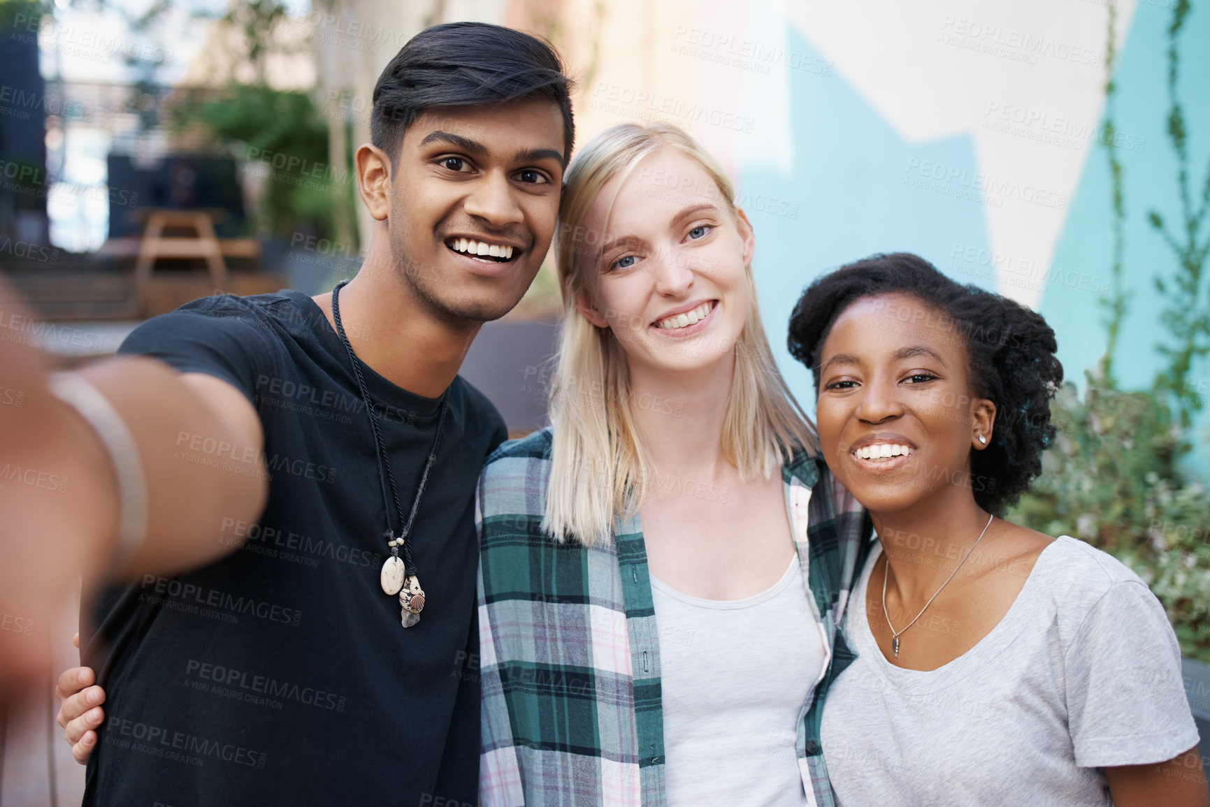 Buy stock photo Shot of a group of happy young friends taking selfies together outside