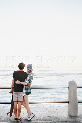 Buy stock photo Couple, rear view and hug on beach for travel with mockup space, adventure and promenade date. Gen z skater, people and skateboard on boardwalk for bonding, embrace and outdoor fun with morning waves