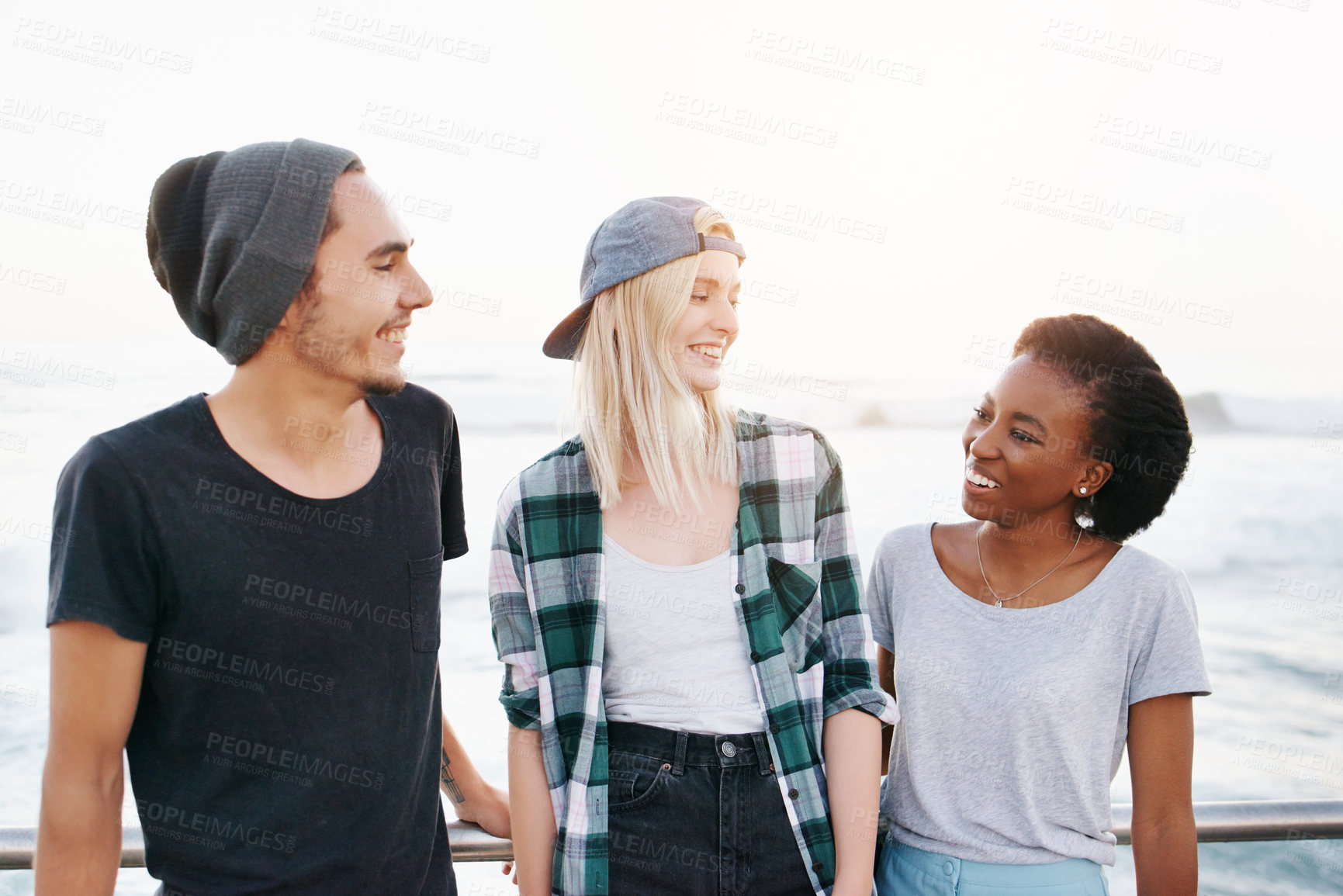 Buy stock photo Cropped shot of a group of young friends standing on the promenade