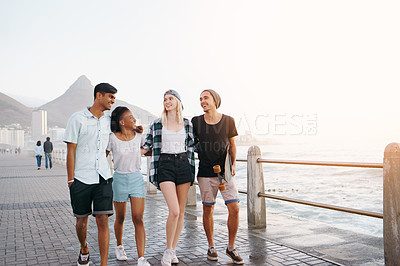 Buy stock photo Happy, walking and friends by sea laugh for holiday, summer vacation and relax outdoors. Diversity, promenade and men and women smile, bonding and talk by ocean for travel, weekend and fun together