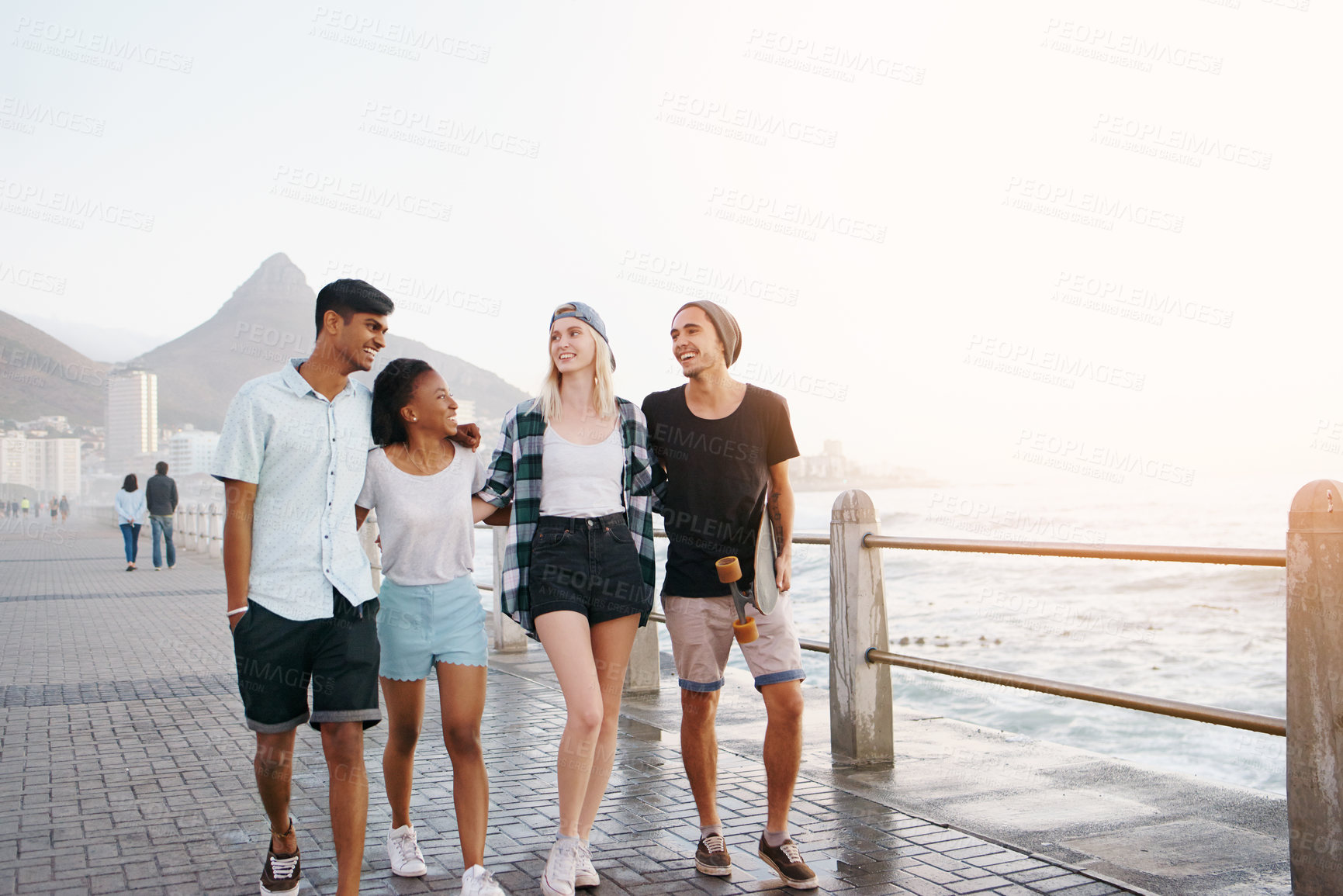 Buy stock photo Happy, walking and friends by sea laugh for holiday, summer vacation and relax outdoors. Diversity, promenade and men and women smile, bonding and talk by ocean for travel, weekend and fun together