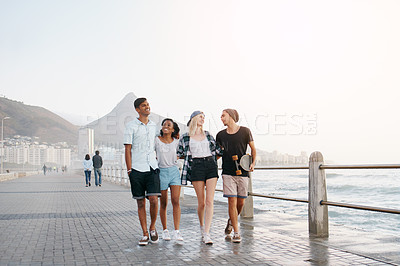 Buy stock photo Group, friends and walk on promenade by ocean with smile for diversity, bonding and space for mockup. Men, women or gen z people with conversation, happy and outdoor on boardwalk by sea for vacation