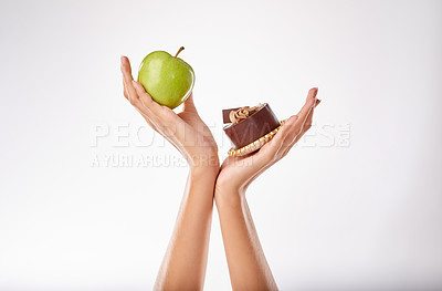 Buy stock photo Studio shot of a woman deciding between healthy and unhealthy foods