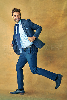 Buy stock photo Studio shot of a handsome young businessman posing against a golden background