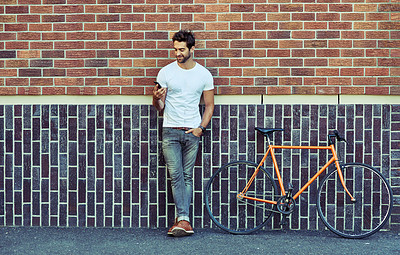 Buy stock photo Man, bicycle and wall in city with phone for transport, cycling for environment with sustainability. Male person, bricks and urban with mobile and bike for travel app, search for route or location
