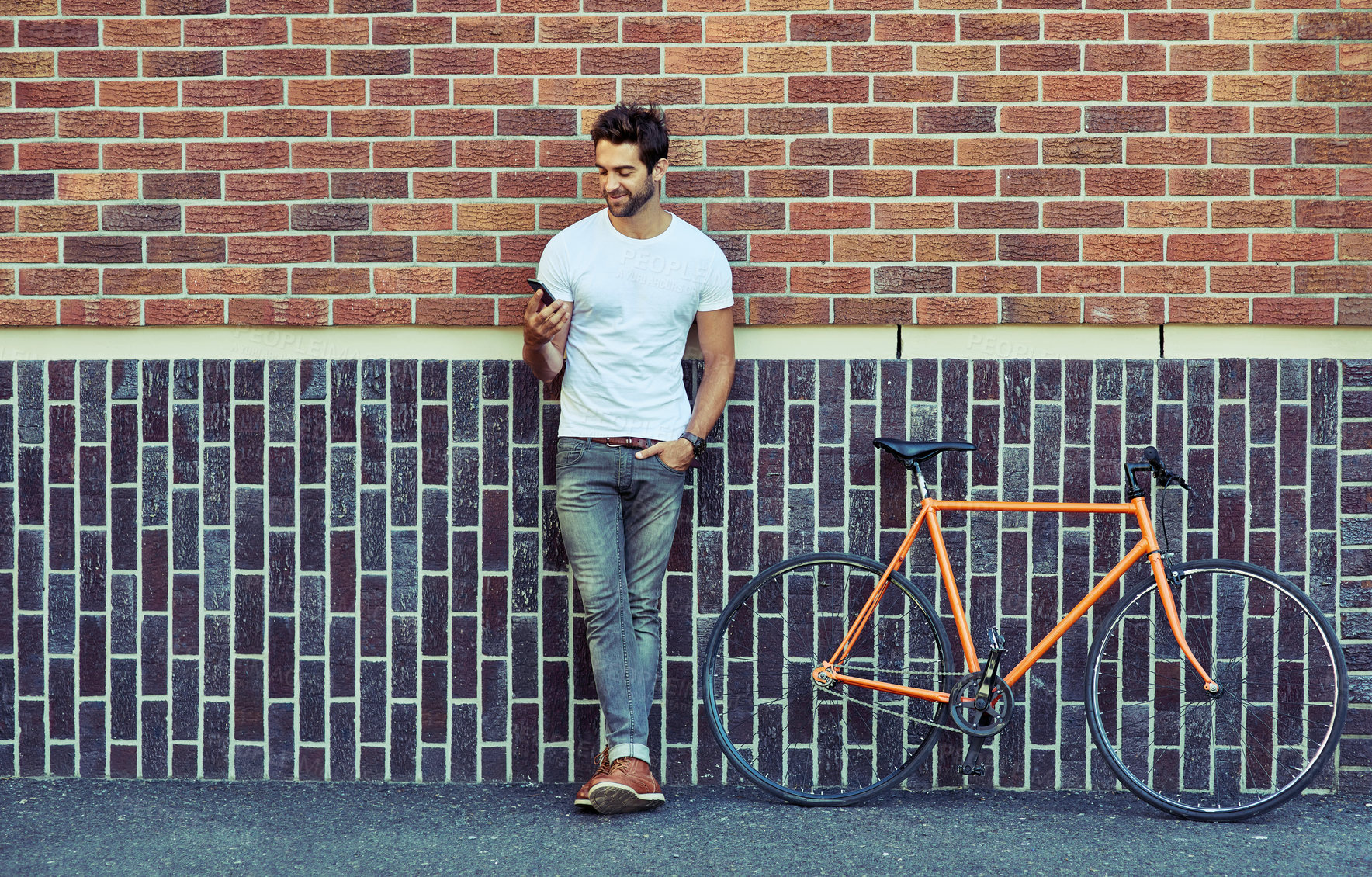 Buy stock photo Man, bicycle and wall in city with phone for transport, cycling for environment with sustainability. Male person, bricks and urban with mobile and bike for travel app, search for route or location