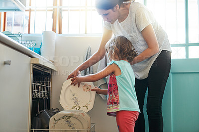 Buy stock photo Shot of a mother and daughter busy at a dishwashing machine