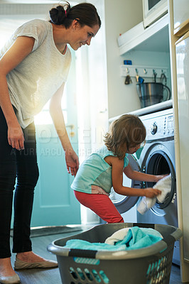 Buy stock photo Help, laundry and mom with kid in home for chores, teaching and learning housekeeping routine. Washing machine, mother and daughter cleaning clothes together with support, care and child development.