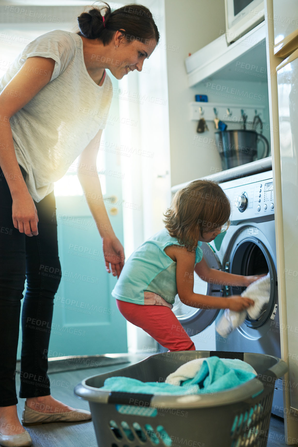 Buy stock photo Help, laundry and mom with kid in home for chores, teaching and learning housekeeping routine. Washing machine, mother and daughter cleaning clothes together with support, care and child development.