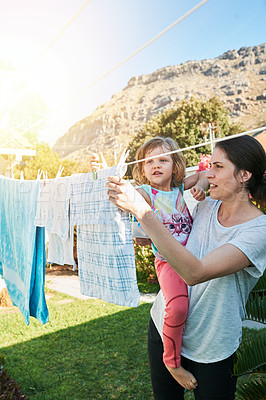 Buy stock photo Backyard, mom and child hanging laundry together with help, teaching and learning chores. Housekeeping, mother and daughter with clean clothes on line outside to sun dry with home, care and bonding.