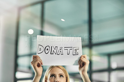 Buy stock photo A woman asking for a donation, charity and help while holding a sign in need of support in a corporate office. Volunteer asking for assistance and crowdfunding from the community and businesses