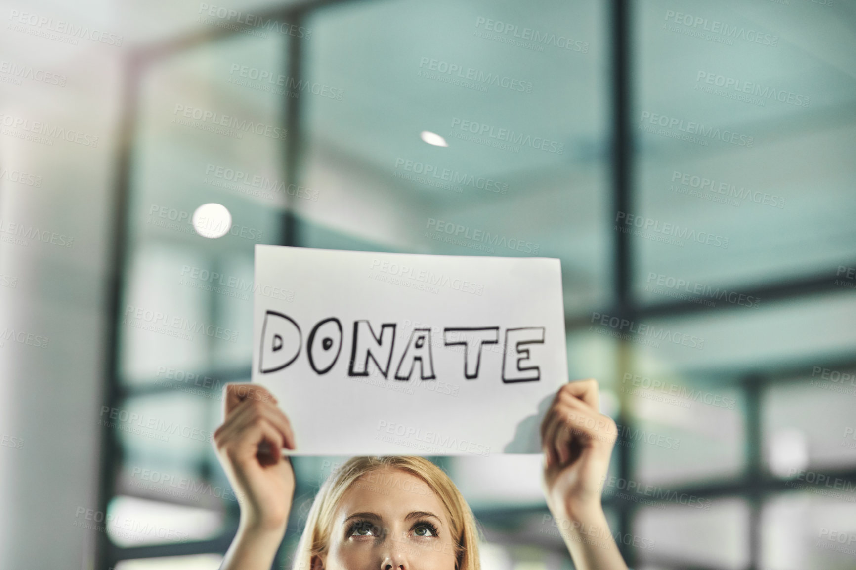 Buy stock photo A woman asking for a donation, charity and help while holding a sign in need of support in a corporate office. Volunteer asking for assistance and crowdfunding from the community and businesses