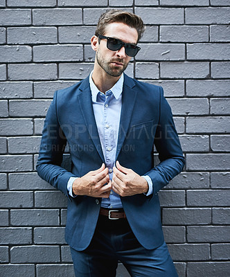 Buy stock photo Shot of a handsome young businessman standing against a grey facebrick wall