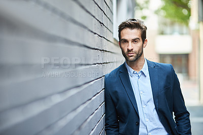 Buy stock photo Shot of a handsome young businessman standing against a grey facebrick wall