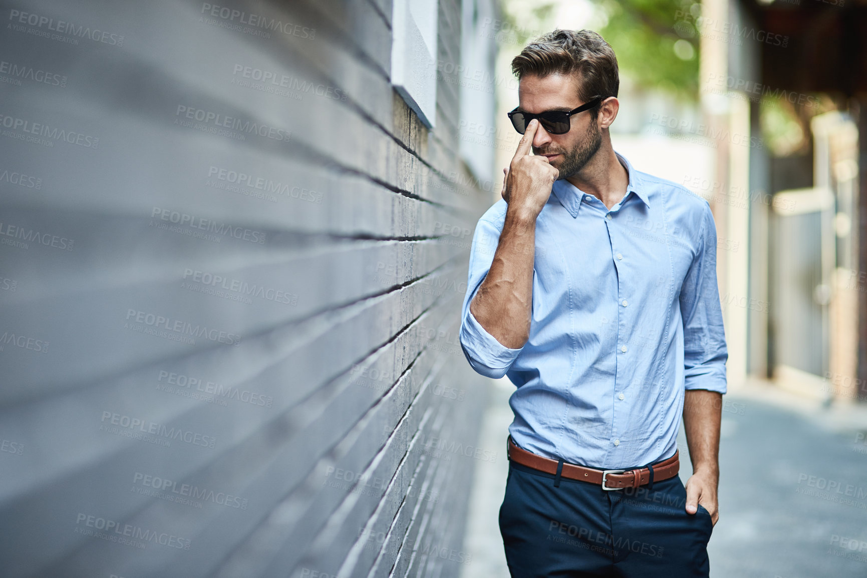 Buy stock photo Sunglasses, fashion and man by brick wall in city with trendy, stylish and classy outfit. Accessory, handsome and male person with elegant shirt and pants for style with confidence in town street.