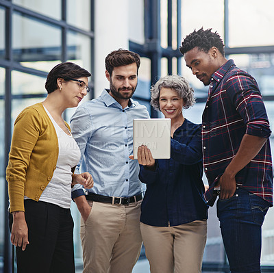 Buy stock photo Shot of a group of colleagues looking at a tablet in the office