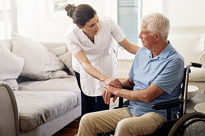 Buy stock photo Shot of a caregiver helping a senior man in a wheelchair at home