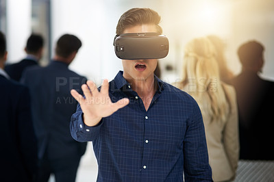 Buy stock photo Shot of a young businessman wearing a VR headset in a busy office