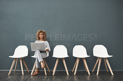 Buy stock photo Shot of a young woman using a laptop while waiting in line for a job interview