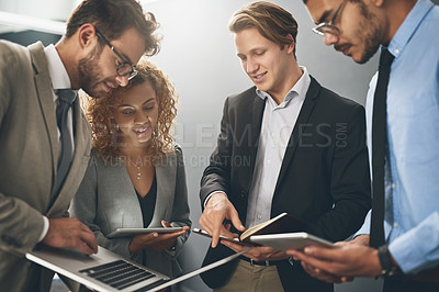 Buy stock photo Shot of a group of businesspeople using digital devices while brainstorming in an office