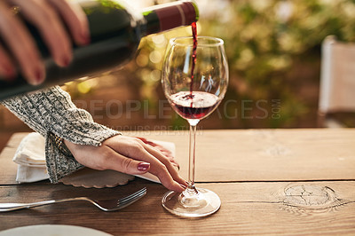 Buy stock photo Glass, bottle and hand of woman pouring wine at a table, calm and content while enjoying free time on a patio. Red wine, hands and lady relax with luxury drink, enjoy a relaxing weekend alone at home