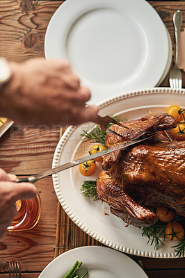 Buy stock photo Hands, food and carving the turkey with a senior man using a knife at a dining room table in his home. Chicken, thanksgiving and tradition with a mature male cutting meat during a roast meal or feast