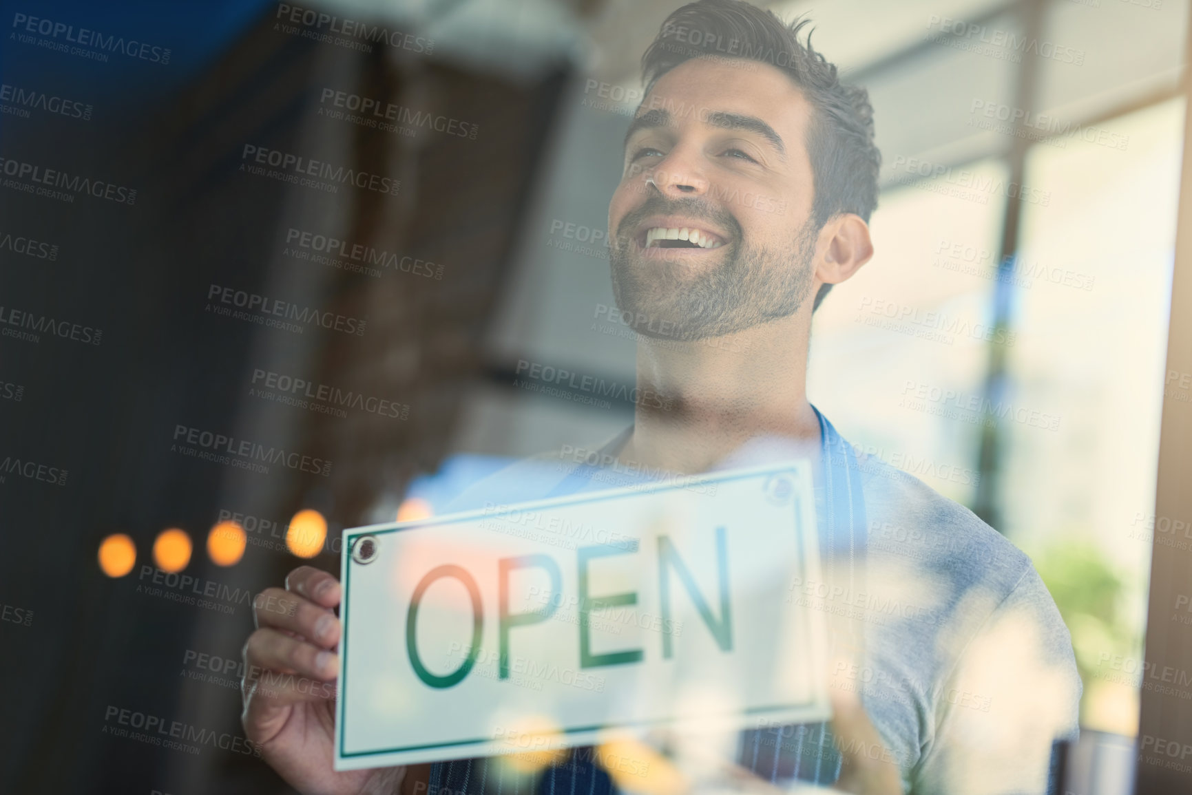 Buy stock photo Happy businessman, cafe and window with open sign for welcome, entrance or small business at indoor restaurant. Young man or owner with smile, billboard or poster ready for service at coffee shop