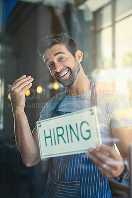 Buy stock photo Portrait of a handsome young man hanging up a hiring sign on the door of his store